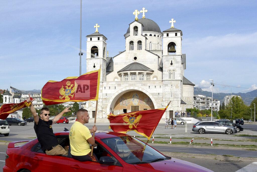 Risto Bozovic Supporters of Democratic Party of Socialists wave Montenegrin flags as they drive in front of the Serbian Orthodox Church of Christ's Resurrection in Podgorica, Montenegro, Thursday, Aug. 27, 2020. Montenegro is holding a parliamentary election this weekend with the pro-Western government facing pressure over the new coronavirus outbreak and ongoing tensions in relations with Serbia and the Serbian Orthodox Church because of a religious property law. (AP Photo/Risto Bozovic)