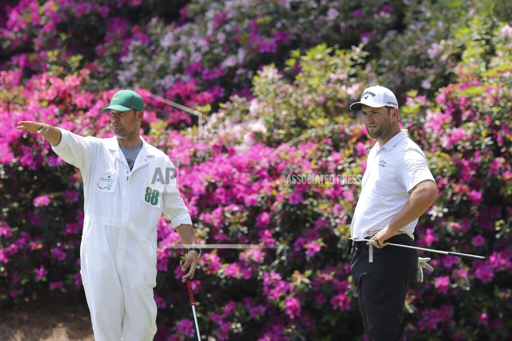 Curtis Compton Caddy Adam Hayes, left, gestures beside Jon Rahm, right, as Rahm prepares to putt on the 13th hole during a practice round for the Masters golf tournament in Augusta, Ga., Wednesday, April 7, 2021. (Curtis Compton/Atlanta Journal-Constitution via AP)