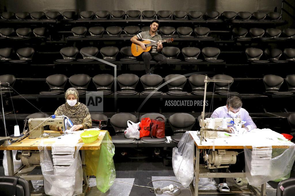Ebrahim Noroozi Volunteers wearing face masks to curb the spread of the new coronavirus sew new masks as a man plays guitar for them at the Hafez theater hall in downtown Tehran, Iran, Wednesday, April 15, 2020. (AP Photo/Ebrahim Noroozi)