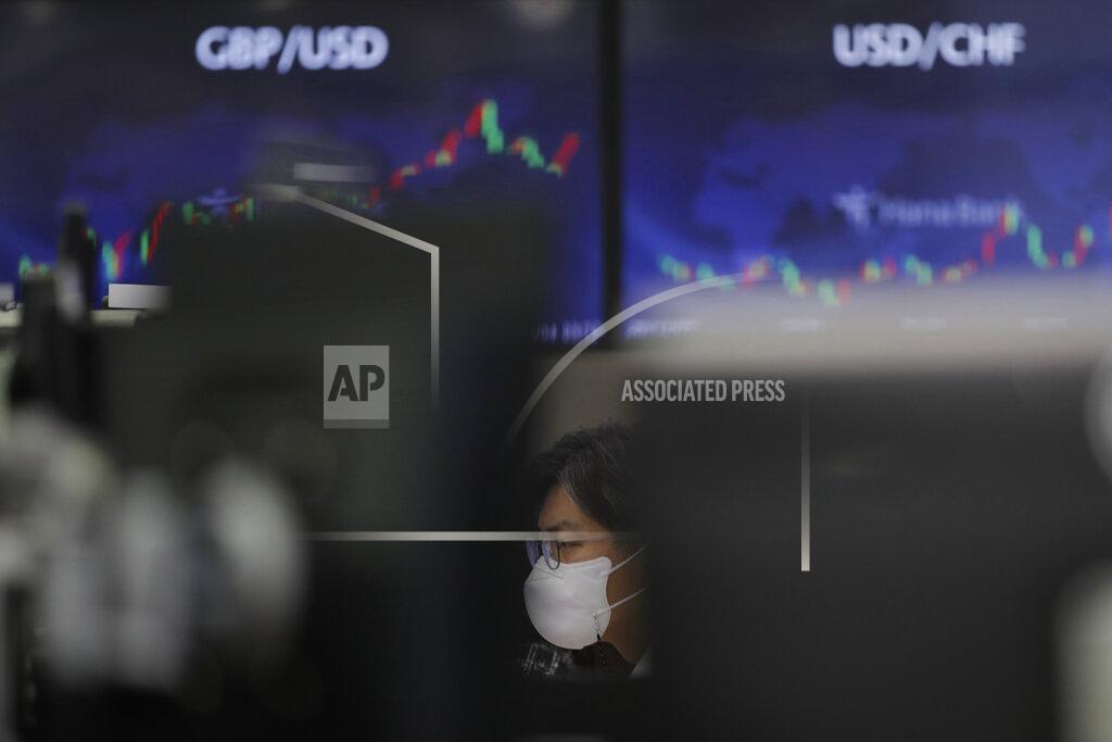 Lee Jin-Man A currency trader watches computer monitors near the screens showing the foreign exchange rates at the foreign exchange dealing room in Seoul, South Korea, Friday, March 12, 2021. Stocks were mixed in Asia on Friday after broad gains lifted several major indexes to all-time highs on Wall Street.(AP Photo/Lee Jin-man)