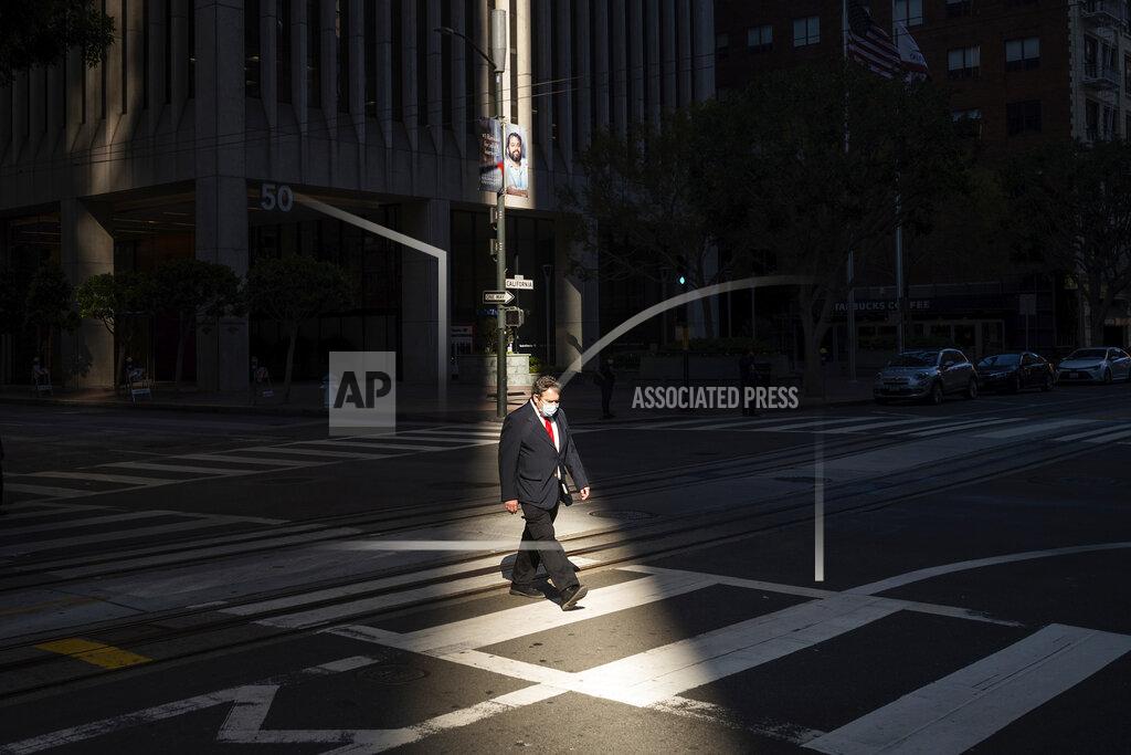 Noah Berger FILE - In this Oct. 21, 2020 file photo, a person crosses an intersection in San Francisco's financial district mid-afternoon, during what would've been a bustling time before the COVID-19 pandemic. California saw its slowest growth rate on record for the nation's most populous state, adding just 21,200 people during the year that ended in July, state officials said Wednesday, Dec. 16, 2020. (AP Photo/Noah Berger, File)