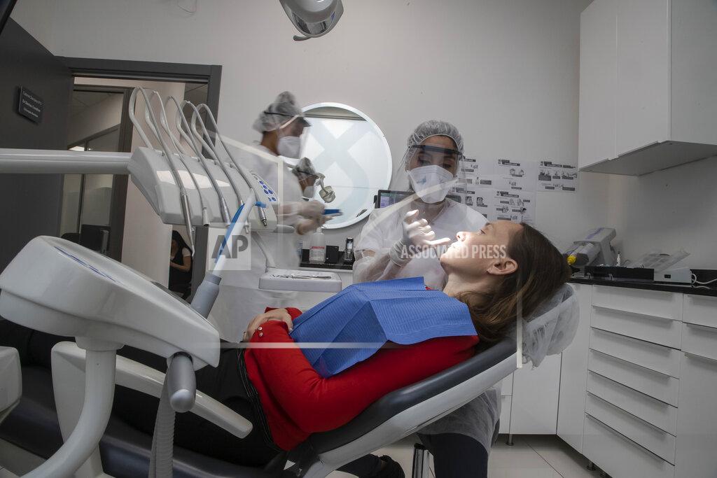 Michel Euler In this Wednesday, May 13, 2020 photo, dentist Sabrine Jendoubi, speaks to patient Veronique Guillot during a dental appointment, at a dental office in Paris. Those with toothache that suffered through France's two-month lockdown, finally have hope to end the pain. Dental practices are cautiously re-opening and non-emergency dentist appointments are now permitted around the country, as the French government eased confinement restrictions from Monday. (AP Photo/Michel Euler)