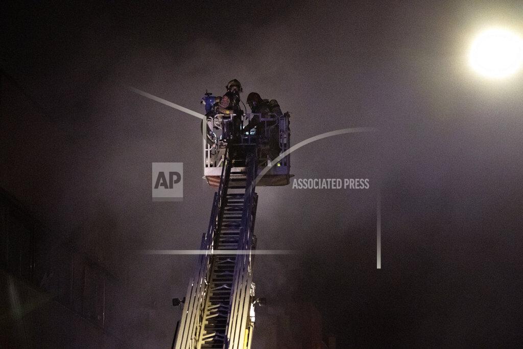 Firefighters work to extinguish a fire at a building in Badalona, Barcelona, Spain, Thursday, Dec. 10, 2020. Authorities in northeastern Spain say a fire has raged through an abandoned building occupied by squatters in the city of Badalona, injuring at least 17 people, including two in critical condition. Firefighters say they rescued around 30 people from windows as the building burned late Wednesday. (AP Photo/Joan Mateu)