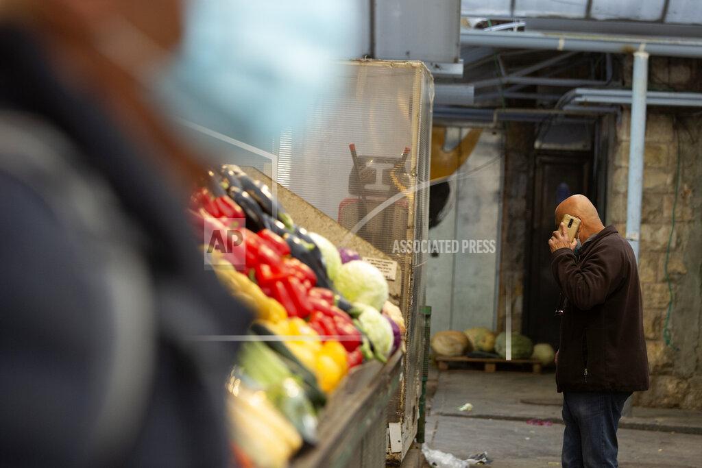 Maya Alleruzzo A man in a protective mask passes another man talking on his mobile phone at the Mahane Yehuda market in Jerusalem, Wednesday, Dec. 23, 2020. In the early days of the pandemic, a panicked Israel began using a mass surveillance tool on its own people, tracking civilians’ mobile phones to halt the spread of the coronavirus. But months later, the tool’s effectiveness is being called into question and critics say its use has come at an immeasurable cost to the country’s democratic principles. (AP Photo/Maya Alleruzzo)