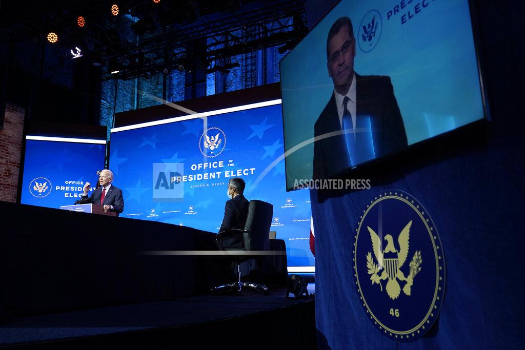 Susan Walsh President-elect Joe Biden speaks during an event at The Queen theater in Wilmington, Del., Tuesday, Dec. 8, 2020, to announce his health care team. Dr. Vivek Murthy, center, who has been nominated by Biden to serve US Surgeon General listens. An image of California Attorney General Xavier Becerra who has been nominated by Biden to serve as secretary of Health and Human Services is displayed on a screen at right. (AP Photo/Susan Walsh)