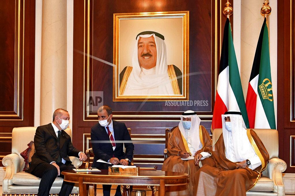 In this photo released by Kuwait News Agency, KUNA, Turkish President Recep Tayyip Erdogan, left, talks to Sheikh Nawaf al-Ahmad al-Sabah, the new Emir of Kuwait, right, in Kuwait, Wednesday, Oct. 7, 2020. The new emir replaced his half-brother, the late ruler Sheikh Sabah al-Ahmad al-Jaber al-Sabah, seen in portrait, who died in the United States at the age of 91 last month. (KUNA via AP)
