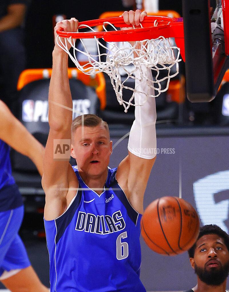 Mike Ehrmann FILE - In this Aug. 21, 2020, file photo, Dallas Mavericks' Kristaps Porzingis (6) dunks against the Los Angeles Clippers during the third quarter of Game 3 of an NBA basketball first-round playoff series in Lake Buena Vista, Fla. Porzingis will miss the start of the season as the Mavericks star continues recovery from surgery to repair a torn meniscus in his right knee. Director of basketball operations Donnie Nelson said in a radio interview Monday, Nov. 16, 2020, the club was being cautious with Luka Doncic's European sidekick, who missed more than a season because of another knee injury.(Mike Ehrmann/Pool Photo via AP, File)