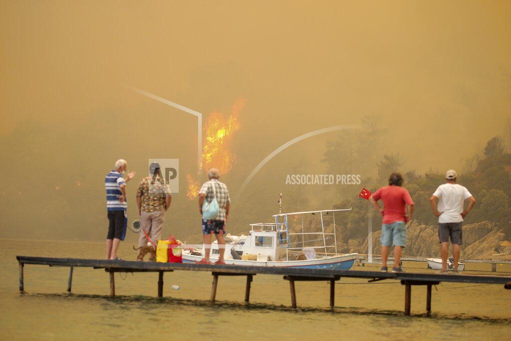 Emre Tazegul Tourists wait to be evacuated from smoke-engulfed Mazi area as wildfires rolled down the hill toward the seashore, in Bodrum, Mugla, Turkey, Sunday, Aug. 1, 2021. More than 100 wildfires have been brought under control in Turkey, according to officials. The forestry minister tweeted that five fires are continuing in the tourist destinations of Antalya and Mugla. (AP Photo/Emre Tazegul)