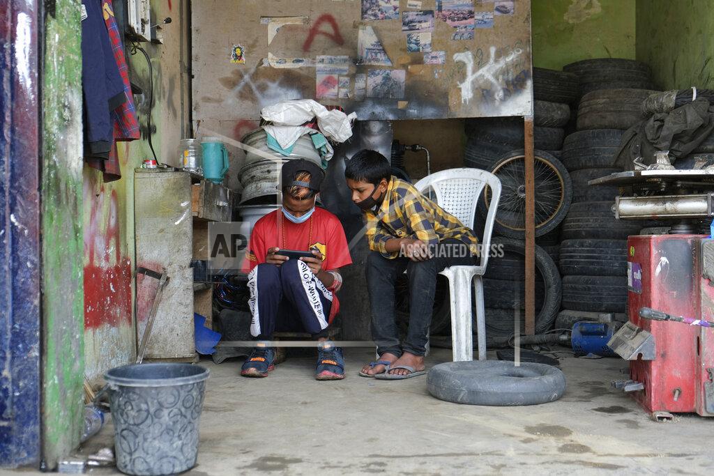 Yirmiyan Arthur Boys wearing face masks take a break as they work at a tire repair shop in Kohima, capital of the northeastern Indian state of Nagaland, Friday, May 29, 2020. India’s economic growth will fall to 4.2% in financial year 2019-20 as compared to 6.1% in the previous year and likely to contract this year because of the coronavirus pandemic. Millions of workers have fled cities after losing their jobs as authorities imposed the lockdown in March and started easing it early this month to promote economic activity. (AP Photo/Yirmiyan Arthur)