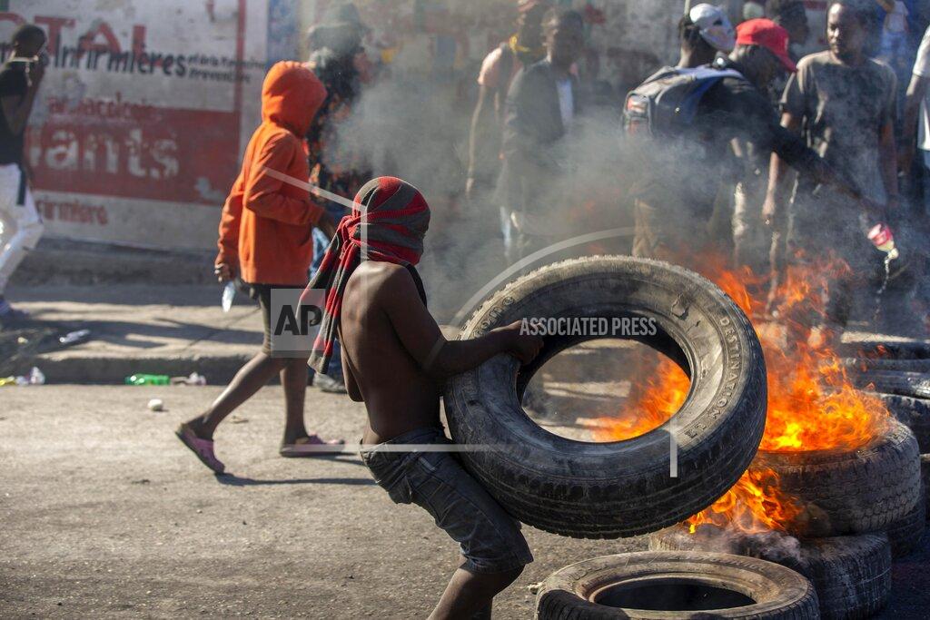 Dieu Nalio Chery A protester sets up a burning barricade during a protest to demand the resignation of Haitian President Jovenel Moise in Port-au-Prince, Haiti, Sunday, Feb. 7, 2021. ( AP Photo/Dieu Nalio Chery)