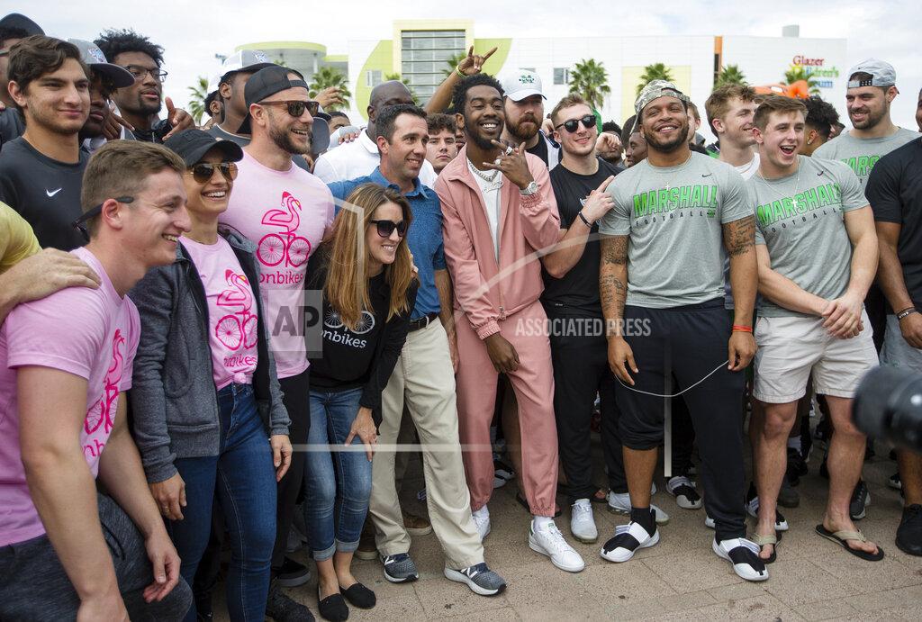 Sholten Singer Desiigner, center, a Brooklyn rapper, poses with Marshall and UCF players before the OnBikes Player Build as part of a Gasparilla Bowl NCAA college football event Friday, Dec. 20, 2019, at Curtis Hixon Park in Tampa, Fla. (Sholten Singer/The Herald-Dispatch via AP)