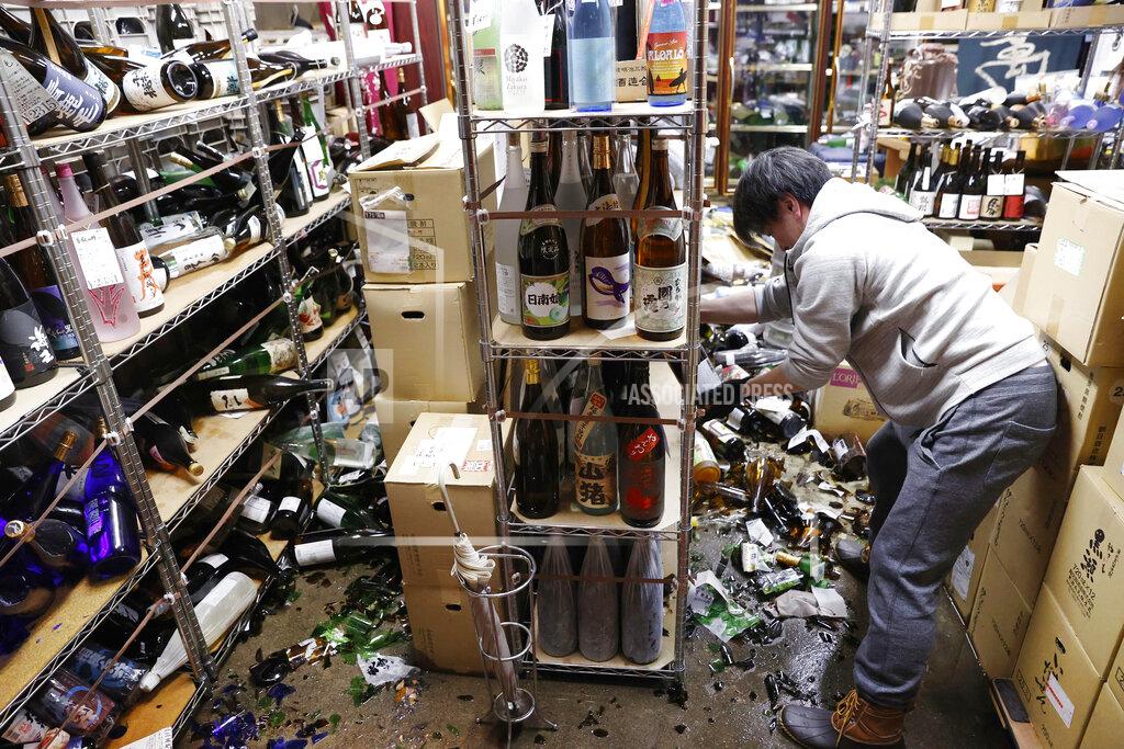 Jun Hirata A liquor shop's manager clears the damaged bottles following an earthquake in Fukushima, northeastern Japan Saturday, Feb. 13, 2021. The Japan Meteorological Agency says a strong earthquake has hit off the coast of northeastern Japan, shaking Fukushima, Miyagi and other areas. (Jun Hirata/Kyodo News via AP)