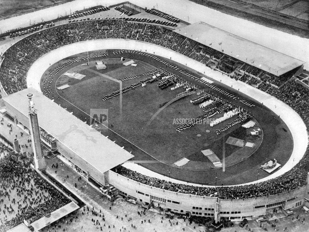 Uncredited In this 1928 photo provided by the International Olympic Committee, the Olympic cauldron stands over the stadium in Amsterdam. The Olympic flame was introduced at the 1928 Amsterdam Olympics. The torch relay began eight years later ahead of the 1936 Berlin Games. (IOC via AP)