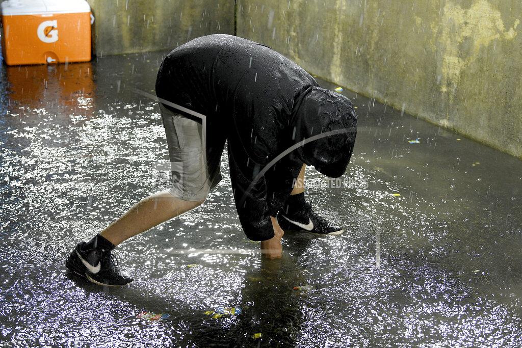 Lon Horwedel A member of the Detroit Tigers grounds crew works to clear the drain in the Milwaukee Brewers dugout during a weather delay at a baseball game in Detroit, Tuesday, Sept. 14, 2021. (AP Photo/Lon Horwedel)