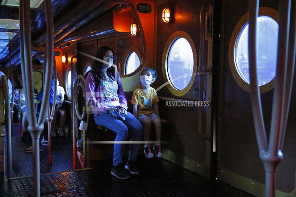 Kin Cheung Guests wearing face masks to prevent the spread of the coronavirus, take an Ocean Express train at the Ocean Park amusement park in Hong Kong, Saturday, June 13, 2020. Hong Kong's Ocean Park reopened Saturday after nearly four months of closure due to the coronavirus pandemic. The animal and nature-themed attraction combines pandas, penguins, roller coasters and other rides, and has been a Hong Kong icon since its opening in 1977. (AP Photo/Kin Cheung)