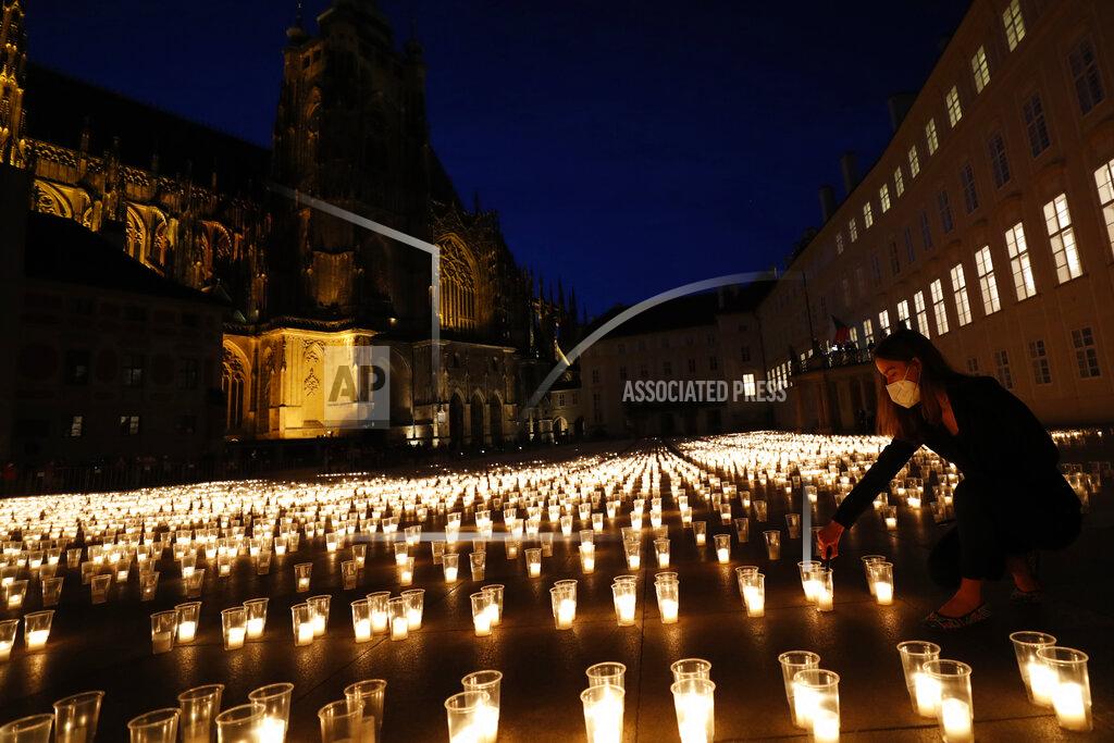 Petr David Josek A woman lights up candles to commemorate victims of the COVD-19 pandemic at the Prague Castle in Prague, Czech Republic, Monday, May 10, 2021. The Czech Republic is massively relaxing its coronavirus restrictions as the hard-hit nation pays respect to nearly 30,000 dead. (AP Photo/Petr David Josek)