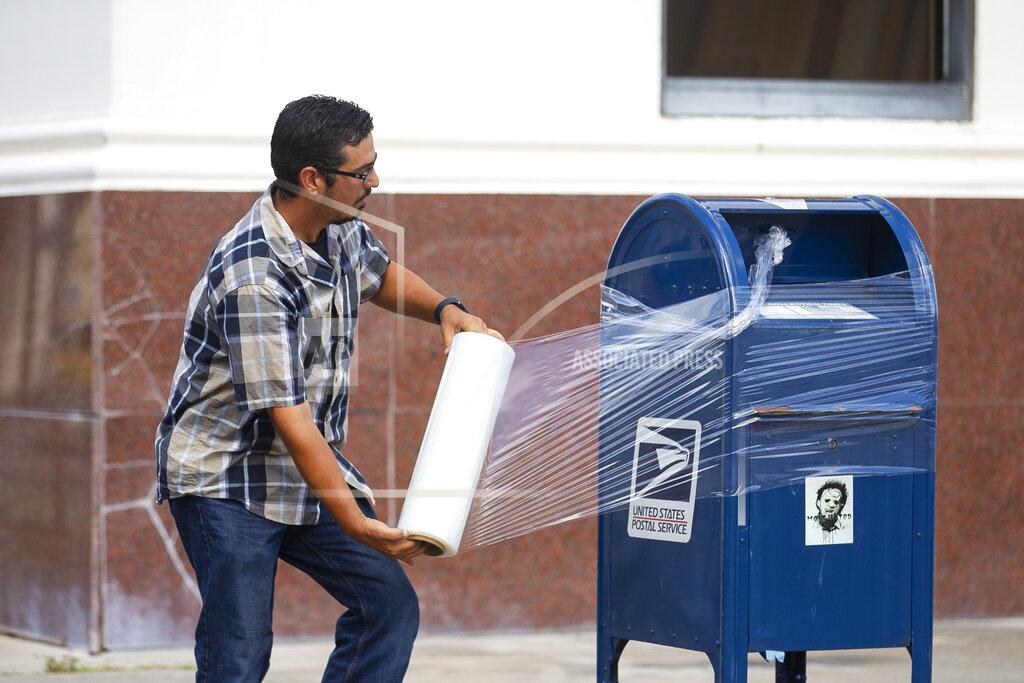 Mark Mulligan A United State Postal Service Employee covers a mailbox with plastic wrap after removing the last mail from it as the island prepares for possible impact from Hurricane Laura, Tuesday, Aug. 25, 2020, in Galveston. The plastic wrap signals that the final mail has been cleared from the box and prevents people from placing more mail inside in case of flooding. (Mark Mulligan/Houston Chronicle via AP)
