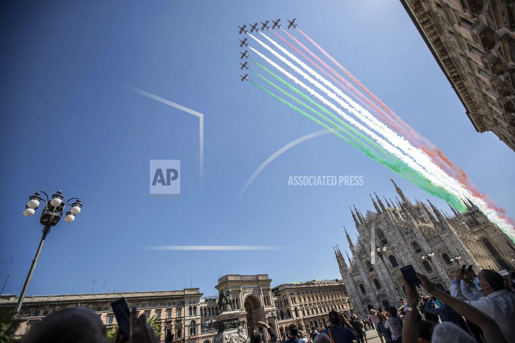 People gather to look at the Frecce Tricolori aerobatic squad of the Italian Air Force fly over Milan's Duomo cathedral, northern Italy, Monday, May 25, 2020 on the occasion of the 74th anniversary of the founding of the Italian Republic on June 2, 1946. This year the acrobatic squad will fly over several Italian cities to bring a message of unity and solidarity during the coronavirus pandemic.(AP Photo/Luca Bruno)