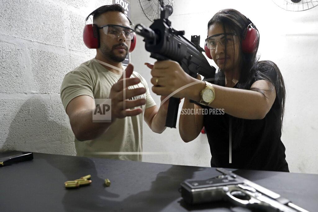 Gisely Nunes learns to handle a submachine gun from an instructor at the Valparaiso Shooting Club on the outskirts of Brasilia, Brazil, Saturday, March 6, 2021. Newly-issued gun decrees, which have worried public security analysts, are to take effect by mid-April unless the Brazilian congress or courts intervene. (AP Photo/Eraldo Peres)