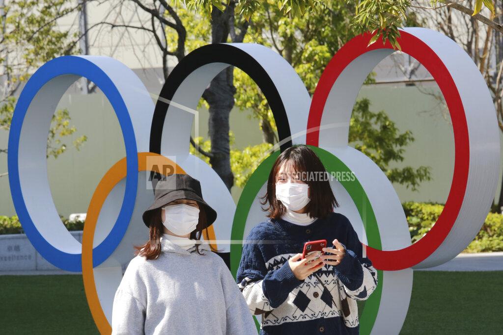 FILE - In this March 17, 2021, file photo, people walk past the Olympic rings in Tokyo. The Tokyo Olympics open in under four months, and the torch relay has begun to crisscross Japan with 10,000 runners. Organizers say they are mitigating the risks, but many medial expert aren't convinced.(AP Photo/Koji Sasahara)