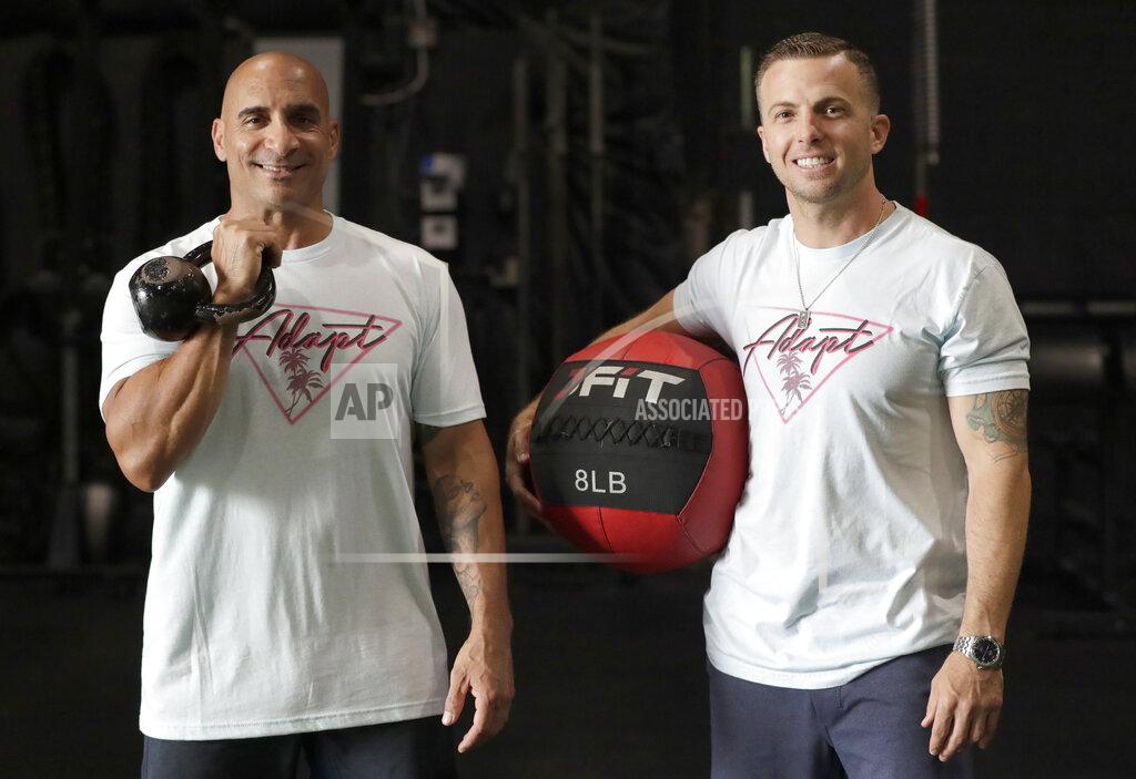 Wilfredo Lee In this Thursday, June 4, 2020, photo, ADAPT gym owners Scott Grondin, right, and Jorge Sanchez pose for a photo at the gym in North Miami, Fla. The business partners and co-founders of the gym just got the OK to reopen their Miami area studio Monday after three months. Desperate to keep their carefully built 15-person team, they gave up their own salaries to keep the entire staff at full pay, relying on them to quickly pivot to online fitness training. (AP Photo/Wilfredo Lee)