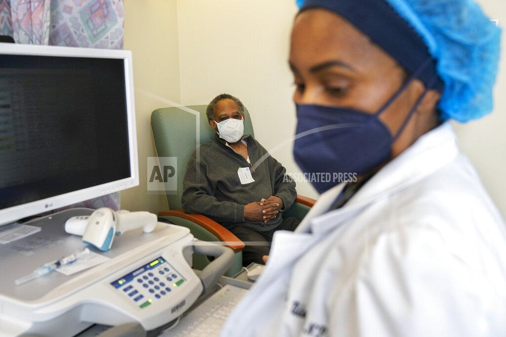 Jacquelyn Martin In this Wednesday, Feb. 10, 2021, photo the Rev. James Coleman, 70, waits as his COVID-19 vaccine is prepared by nurse practitioner Ifreke Udodong, at United Medical Center in southeast Washington. (AP Photo/Jacquelyn Martin)