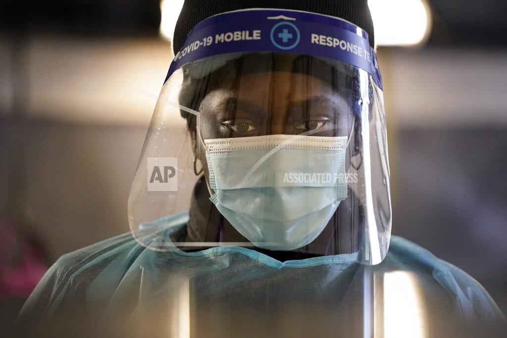 FILE - In this Dec. 8, 2020, file photo, a health care worker wears personal protective equipment as she speaks to a patient at a mobile testing location for COVID-19 in Auburn, Maine. Doctors and nurses around the U.S. are becoming exhausted and demoralized as they struggle to cope with a record-breaking surge of COVID-19 patients that is swamping hospitals and prompting governors to clamp back down to contain the virus. (AP Photo/Robert F. Bukaty, File)
