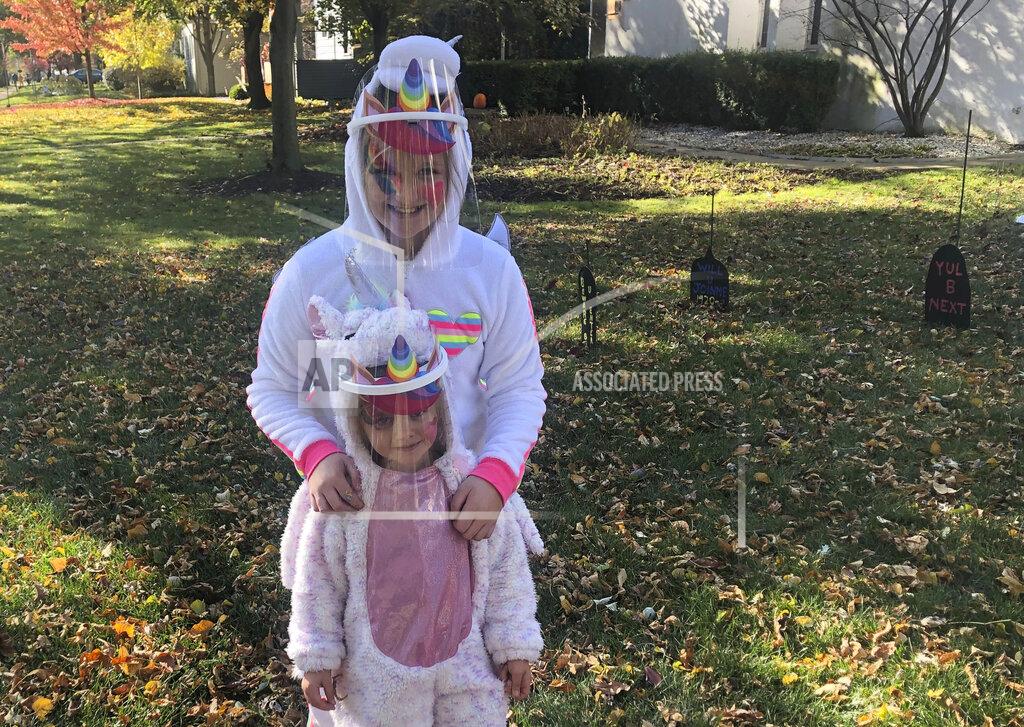 Don Babwin Ten-year-old Cameron Fox and her 4-year-old sister, Lexi, of Brookfield, Ill., are dressed as unicorns for Halloween with plastic face shields to protect against COVID-19, as they visit the home of family friends in nearby River Forest, Ill., on Saturday, Oct. 31, 2020. Their grandmother bought the shields as their mother, Julie, is taking them to visit the homes of friends and family in the area, in pace of the traditional trick-or-treating. (AP Photo/Don Babwin)