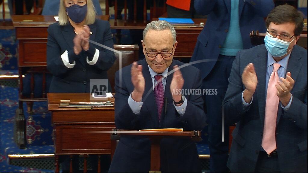 Uncredited In this image from video, Senate Majority Leader Chuck Schumer of N.Y., leads a round of applause for support staff as he speaks before the final vote on the Senate version of the COVID-19 relief bill in the Senate at the U.S. Capitol in Washington, Saturday, March 6, 2021. (Senate Television via AP)