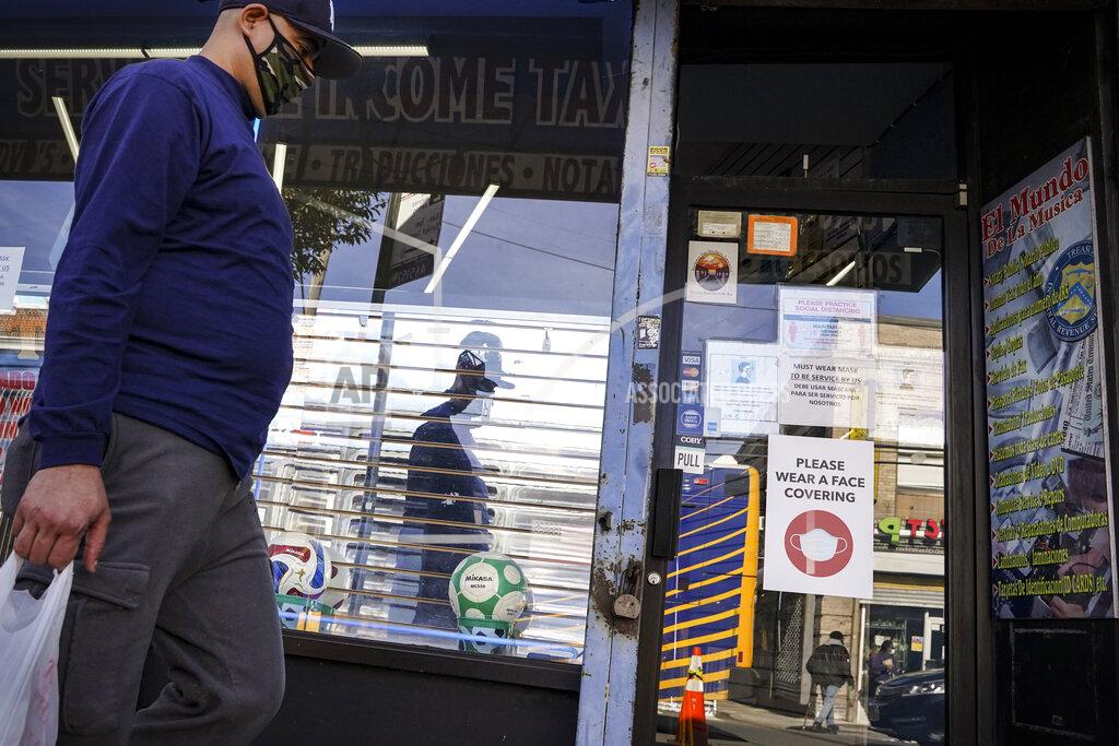 John Minchillo A pedestrian in a mask passes shuttered storefronts on Thursday, Oct. 15, 2020, as restrictions are imposed on the area due to an increase in COVID-19 infections in the Far Rockaway neighborhood of the borough of Queens in New York. After shutdowns swept entire nations during the first surge of the coronavirus earlier this year, some countries and U.S. states are trying more targeted measures as cases rise again around the world. (AP Photo/John Minchillo)