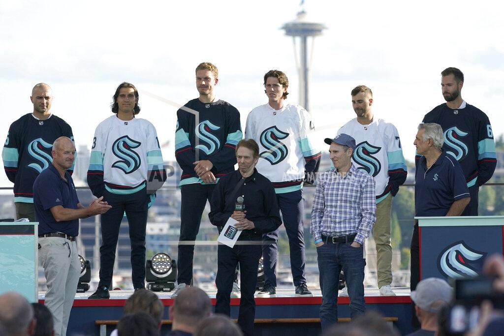 Ted S. Warren New Seattle Kraken NHL hockey players, back row from left, Mark Giordano, Brandon Tanev, Jamie Oleksiak, Hadyn Fluery, Jordan Eberle and Chris Dreidger stand on stage with Kraken owners David Wright, front left, Jerry Bruckheimer, front center, and Andy Jassy, front second from right, and Kraken general manager Ron Francis, front right, Wednesday, July 21, 2021, after being introduced during the Kraken's expansion draft event in Seattle. Jassy is also president and CEO of Amazon.com. (AP Photo/Ted S. Warren)