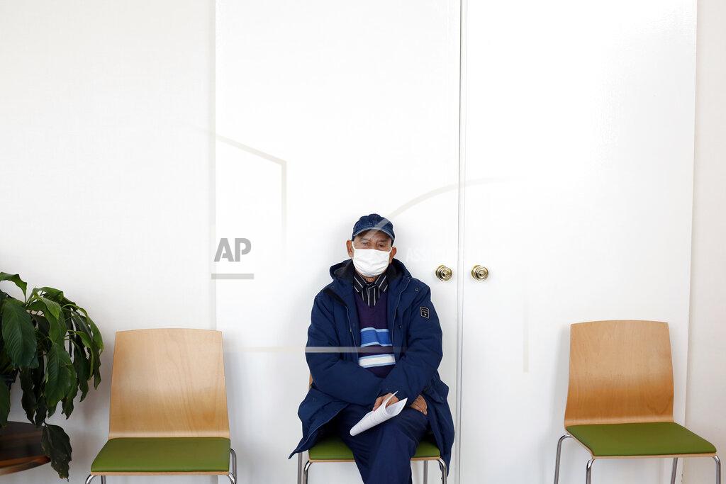 Uncredited FILE - In this Jan. 18, 2021, file photo, a man waits prior to receiving the Pfizer-BioNTech COVID-19 vaccine at a center in Saint-Denis, north of Paris. Many people lining up for vaccines in the Paris suburb are particularly grateful for the injections. The surrounding region is the poorest in mainland France, with 130 languages spoken and the country's highest rise in mortality last spring. (AP Photo/Thibault Camus)