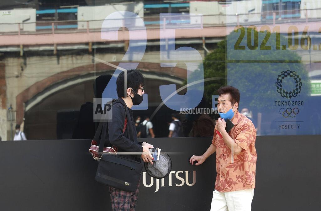 People talk by as a countdown clock shows 25 days to the opening ceremony of the Tokyo 2020 Olympic and Paralympic Games, in Tokyo, Monday, June 28, 2021. (AP Photo/Koji Sasahara)
