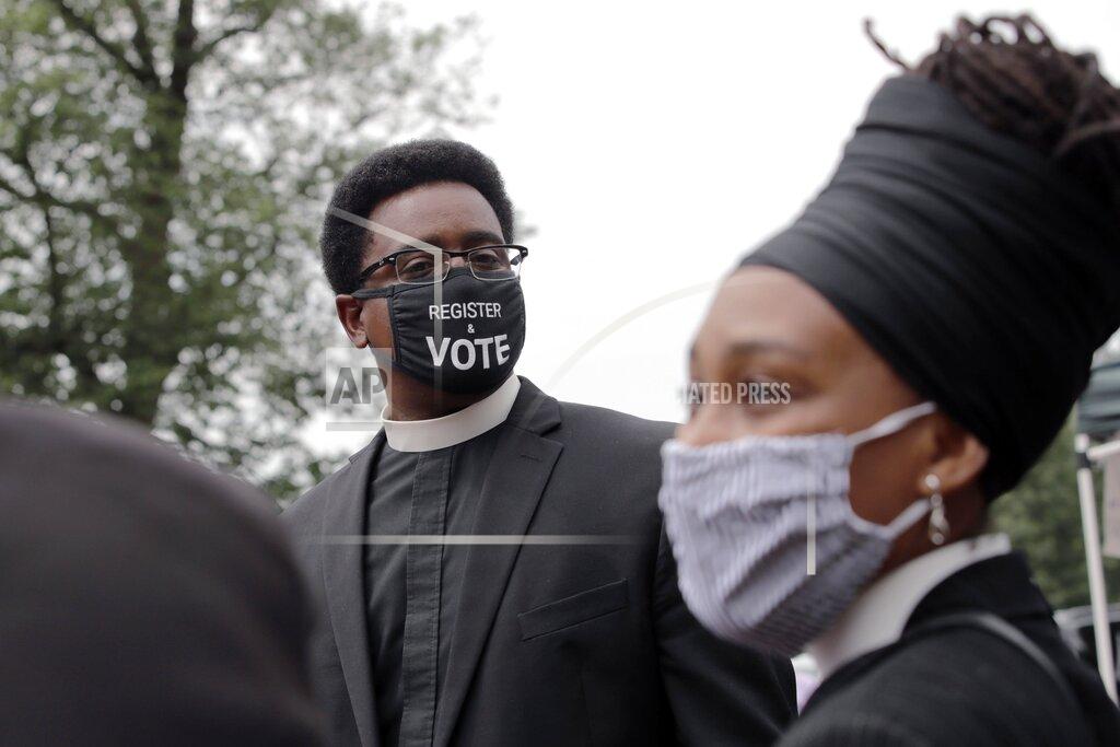Charles Krupa FILE - In this Monday, July 20, 2020 file photo, the Rev. Rahsaan Hall, of the St. Paul AME Church in Cambridge, Mass., wears a mask which reads, "Register & Vote" outside the Statehouse in Boston, on a day when thousands across the country planned to walked off the job to protest systemic racism and economic inequality that has worsened during the coronavirus pandemic. (AP Photo/Charles Krupa)