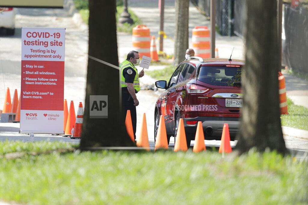 Brynn Anderson An official holds a sign telling people to "Show Your Photo ID and Appointment Confirmation" to help guide patients to a COVID-19 testing area on Georgia Tech's campus, Monday, April 6, 2020, in Atlanta. (AP Photo/Brynn Anderson)