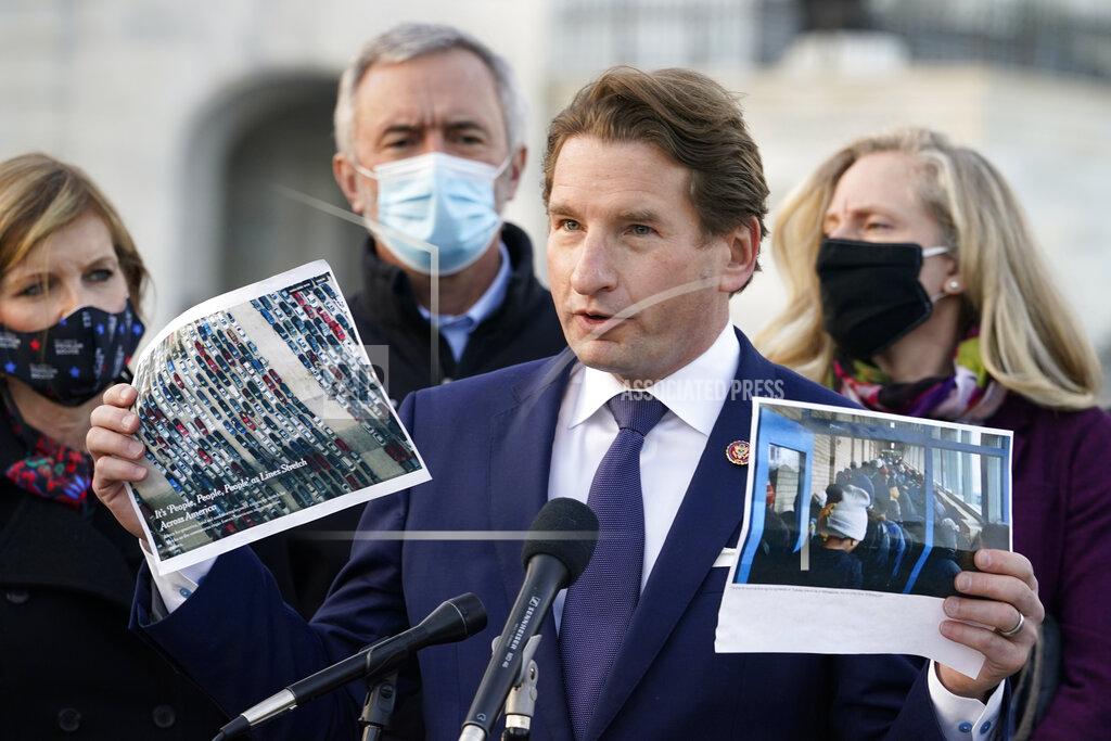 Jacquelyn Martin Rep. Dean Phillips, D-Minn., holds up images of people in America standing in food distribution lines, as he speaks during a news conference with the Problem Solvers Caucus, Monday, Dec. 21, 2020, on Capitol Hill in Washington. Congressional leaders have hashed out a massive, year-end catchall bill that combines $900 billion in COVID-19 aid with a $1.4 trillion spending bill and reams of other unfinished legislation on taxes, energy, education and health care. (AP Photo/Jacquelyn Martin)