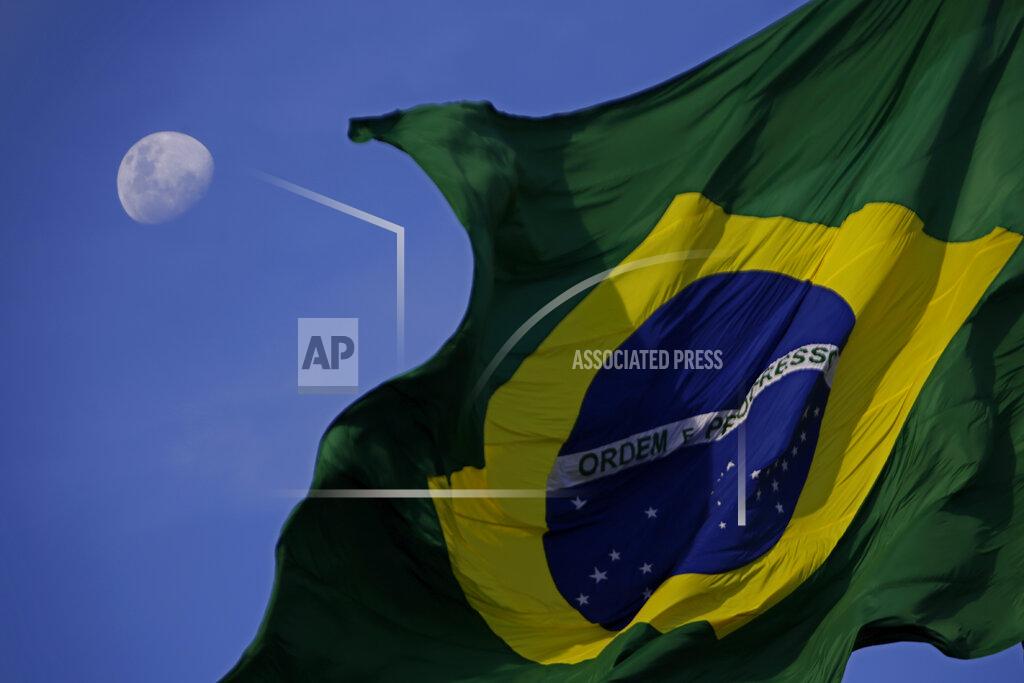 The Brazilian flag flies with the moon behind it during a protest against the government's response in combating COVID-19 and demanding the impeachment of Brazil's President Jair Bolsonaro, in Brasilia, Brazil, Sunday, Jan. 24, 2021. (AP Photo/Eraldo Peres)