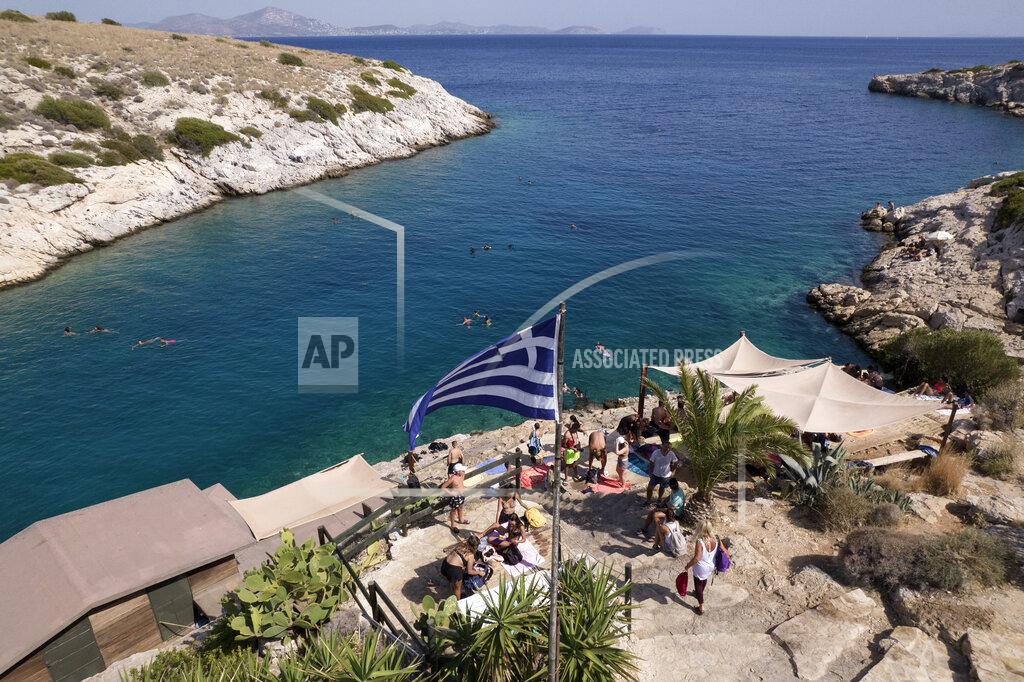 Yorgos Karahalis People are pictured next to a beach bar at Vouliagmeni suburb, southwest of Athens, on Thursday, July 29, 2021. One of the most severe heat waves recorded since 1980s scorched southeast Europe on Thursday, sending residents flocking to the coast, public fountains and air-conditioned locations to find some relief, with temperatures rose above 40 C (104 F) in parts of Greece and across much of the region. (AP Photo/Yorgos Karahalis)