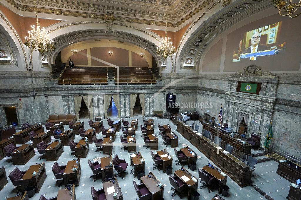 Ted S. Warren FILE - In this Jan. 13, 2021 file photo, a pre-recorded video of Washington Gov. Jay Inslee giving his inaugural address is played in the Senate chambers at the Capitol in Olympia, Wash., during a joint session of the Washington Legislature being held remotely. The 2021 session of the Washington Legislature ended Sunday, April 25 and lawmakers had no shortage of weighty topics to consider while having to conduct their work amid a pandemic that meant most meetings and votes were conducted remotely. The Capitol building was also closed to the public since last year due to the COVID-19 pandemic, and was surrounded by security fencing and national guard members at times due to fears of protests. (AP Photo/Ted S. Warren, File)
