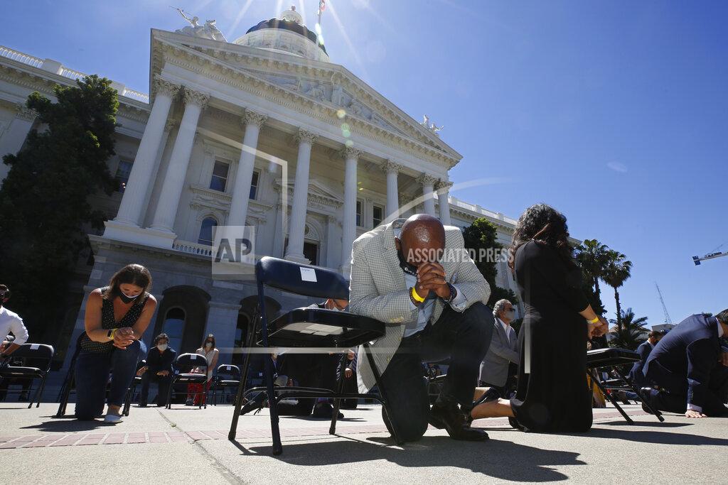 Rich Pedroncelli FILE - In this June 9, 2020, file photo, Assemblyman Mike Gipson, D-Carson, bows his head as he and other members of the California Legislature kneel to honor George Floyd at the Capitol in Sacramento, Calif. Lawmakers approved, Thursday, Sept. 9, 2021, Gipson's measure that would prohibit police from using techniques that create a substantial risk of what's known as "positional asphyxia." (AP Photo/Rich Pedroncelli, File)