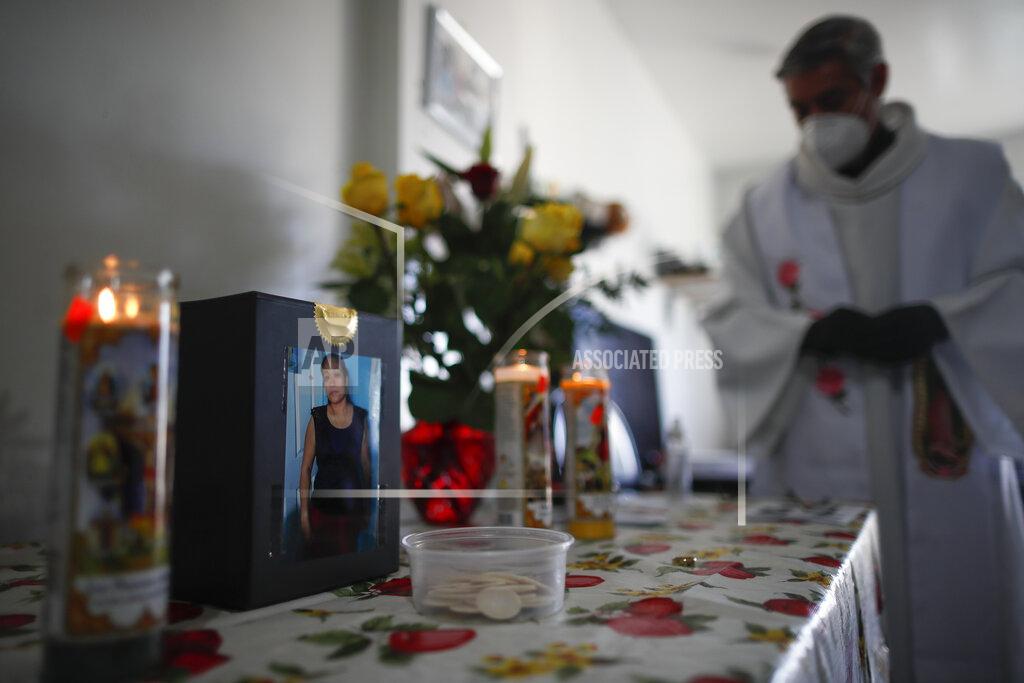 John Minchillo Fabian Arias, a Lutheran pastor with Saint Peter's Church in Manhattan, stands beside a box containing the ashes of Graciela Ruiz Martinez who died of COVID-19 before offering an in-home funeral service, Sunday, May 10, 2020, in the Queens borough of New York. (AP Photo/John Minchillo)