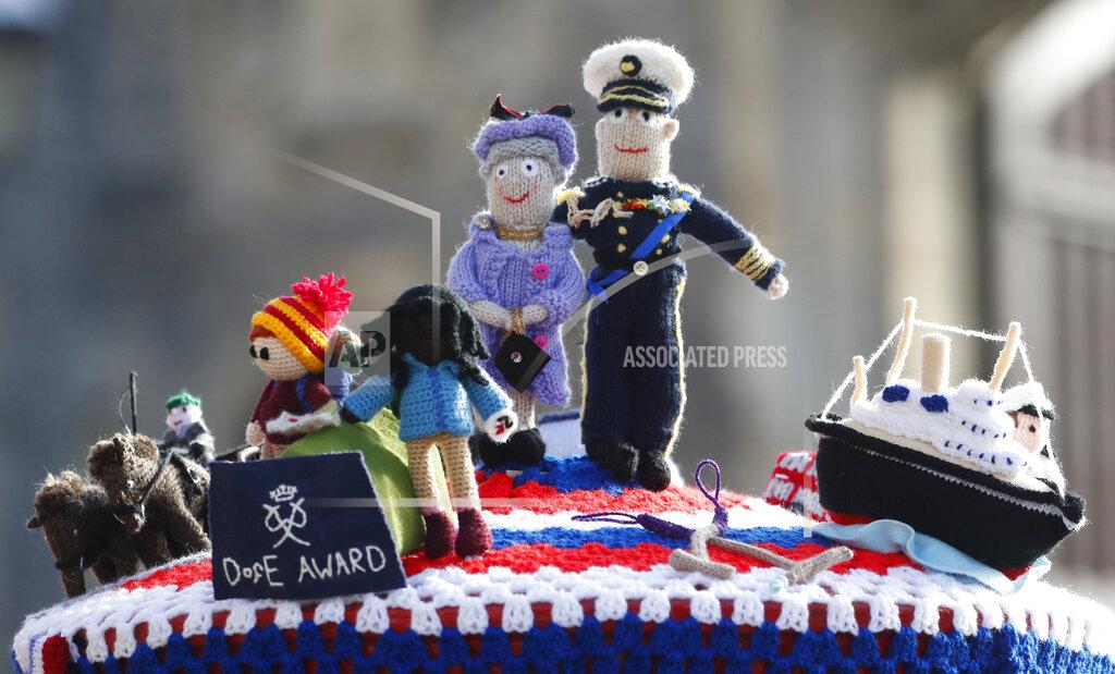 Alastair Grant A knitted top cover for a post box depicting Britain's Queen Elizabeth II and her husband Prince Philip in Windsor, England, Friday, April 16, 2021. Prince Philip husband of Britain's Queen Elizabeth II died April 9, aged 99, his funeral will take place Saturday at Windsor Castle in St George's Chapel. The knitted top show some of Prince Philips favorites: the Royal Yacht Britannia, right, the Duke of Edinburgh award scheme for young people and his hobby of carriage driving . (AP Photo/Alastair Grant)