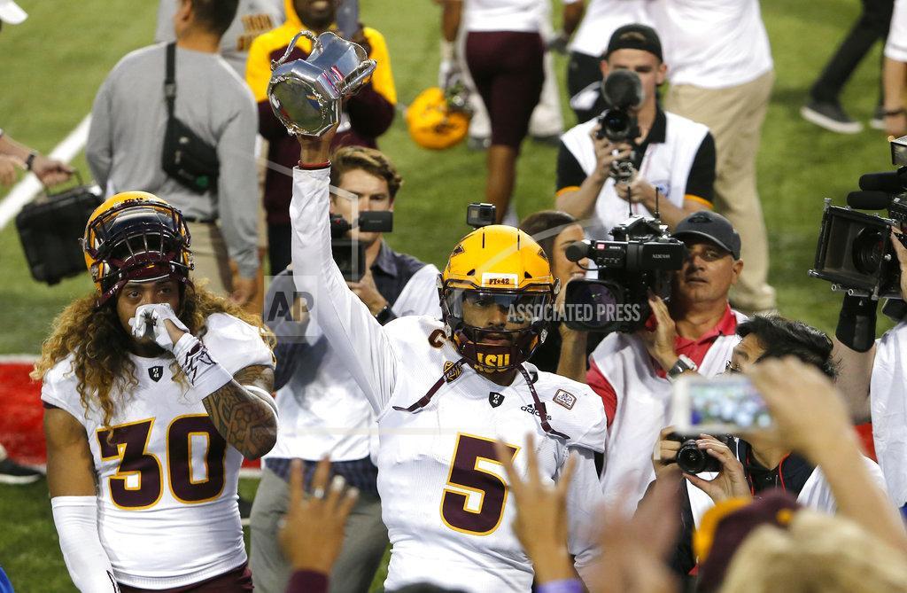 Rick Scuteri Arizona State quarterback Manny Wilkins (5) celebrates with fans by holding up the Territorial Cup after defeating Arizona in an NCAA college football game, Saturday, Nov. 24, 2018, in Tucson, Ariz. (AP Photo/Rick Scuteri)