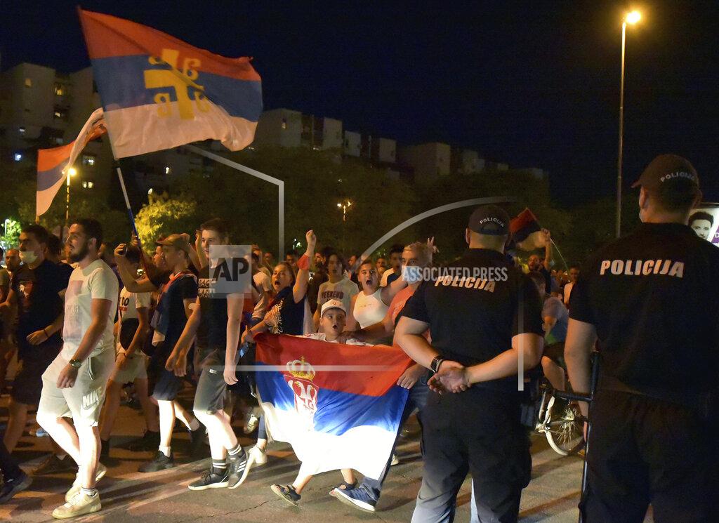 Risto Bozovic Police officers, right, watch opposition supporters wave Serbian flags during church-led protest in Podgorica, Montenegro, Thursday, Aug. 27, 2020. Montenegro is holding a parliamentary election this weekend with the pro-Western government facing pressure over the new coronavirus outbreak and ongoing tensions in relations with Serbia and the Serbian Orthodox Church because of a religious property law. (AP Photo/Risto Bozovic)