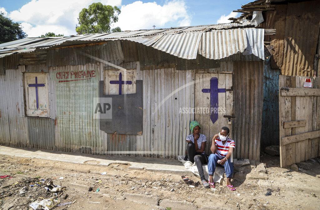 Patrick Ngugi FILE - In this Sunday, April 12, 2020 file photo, two residents sit outside a closed church, after religious public services were stopped to limit the spread of the coronavirus, in the Mathare slum, or informal settlement, of Nairobi, Kenya. The COVID-19 pandemic is testing the patience of some religious leaders across Africa who worry they will lose followers, and funding, as restrictions on gatherings continue. (AP Photo/Patrick Ngugi, File)