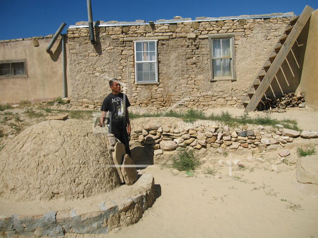 Beth Harpaz FILE - This Oct. 1, 2012 photo shows tour guide Robert Francis gesturing toward an outdoor oven outside an adobe dwelling on a tour of the Acoma Pueblo at the Sky City Cultural Center west of Albuquerque in New Mexico. Tours of the pueblo tell the story of the Acoma people, who have lived on a mesa 370 feet above the desert floor for nearly 1,000 years, surviving centuries of challenges from the Spanish conquistadors to modern times. The location is featured in a collection of mini-essays by American writers published online by the Frommer's guidebook company about places they believe helped shape and define America. (AP Photo/Beth Harpaz, File)