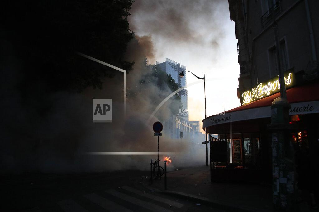 Michel Euler A restaurant and a burning barricade are pictured during a demonstration Tuesday, June 2, 2020 in Paris. Paris riot officers fired tear gas as scattered protesters threw projectiles and set fires at an unauthorized demonstration against police violence and racial injustice. Several thousand people rallied peacefully for two hours around the main Paris courthouse in homage to George Floyd and to Adama Traore, a French black man who died in police custody. (AP Photo/Michel Euler)