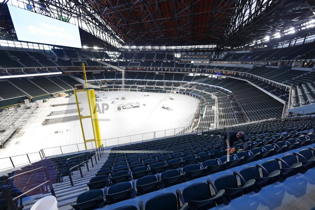 Worker Raul Camacho clean seats inside the newly constructed Globe Life Field in Arlington Texas, Wednesday, March 11, 2020. The potential of games played this fall with reduced crowds or no fans at all, coupled with new expenses in making a facility go, are a big reason why four-year colleges have been forced to cut approximately 100 programs entirely. (AP Photo/Tony Gutierrez)