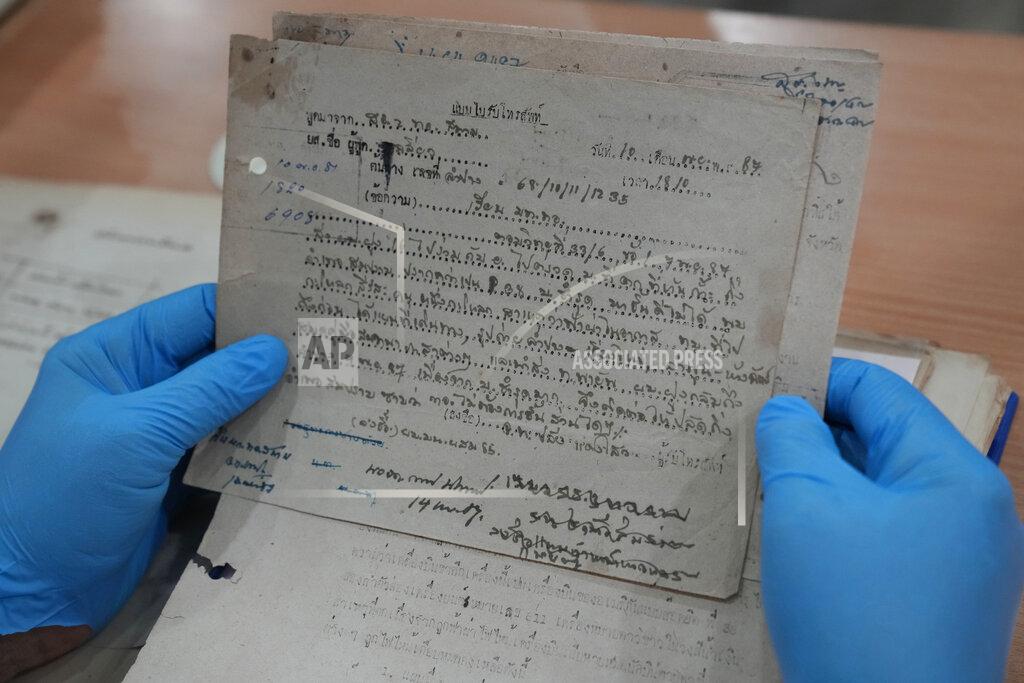 Sakchai Lalit Retired Thai Air Chief Marshal Sakpinit Promthep looks at a WWII-era local Thai police report, in the archive room of the Thai Air Force Museum, In Bangkok, Thailand, Friday April 29, 2022. The document helped locate the possible remains of a U.S. pilot, missing from that time, from a crash site in Lampang province. documenting the crash of a U.S. P-38 plane. (AP Photo/Sakchai Lalit)
