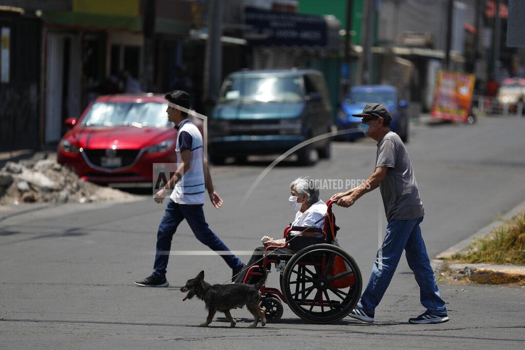 Rebecca Blackwell A man pushes a woman in a wheelchair as a dog walks alongside them, in the Iztapalapa district of Mexico City, Tuesday, May 5, 2020. Iztapalapa has the most confirmed cases of the new coronavirus within Mexico's densely populated capital, itself one of the hardest hit areas of the country, with thousands of confirmed cases and around 500 deaths.(AP Photo/Rebecca Blackwell)